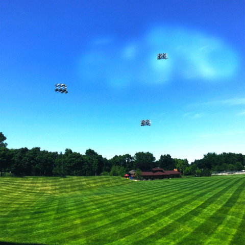 Photograph taken at a park after the grass was mowed. There are things floating in the sky, maybe spaceship, maybe ufos, maybe drones that no one can identify but aren't concerning