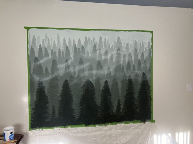 A mural for a pine forest scene. The painters tape is still up around the painting.